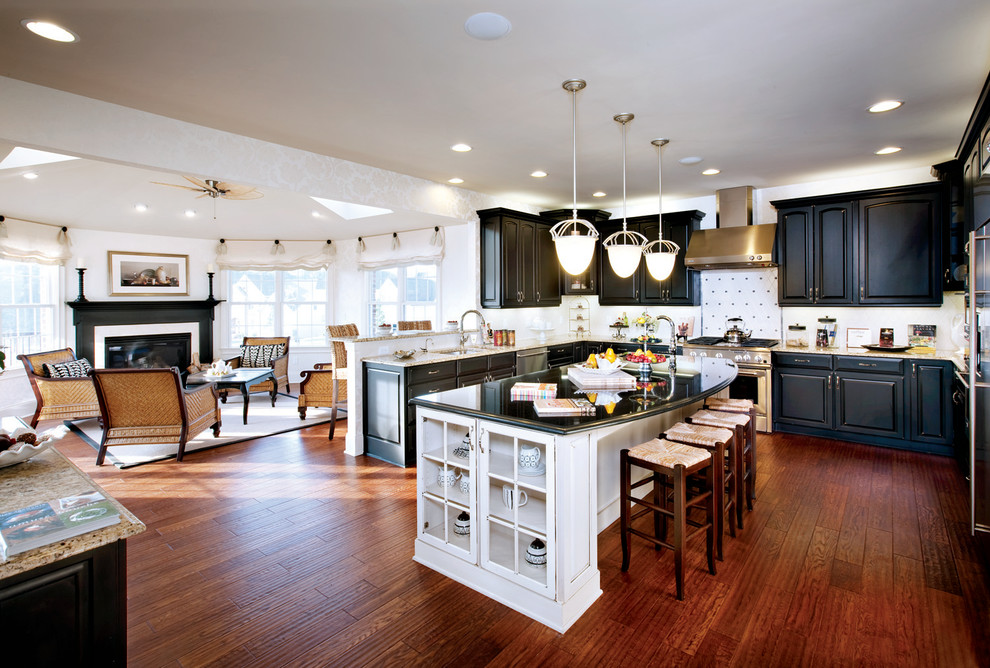 Example of a classic u-shaped open concept kitchen design with raised-panel cabinets, black cabinets and white backsplash