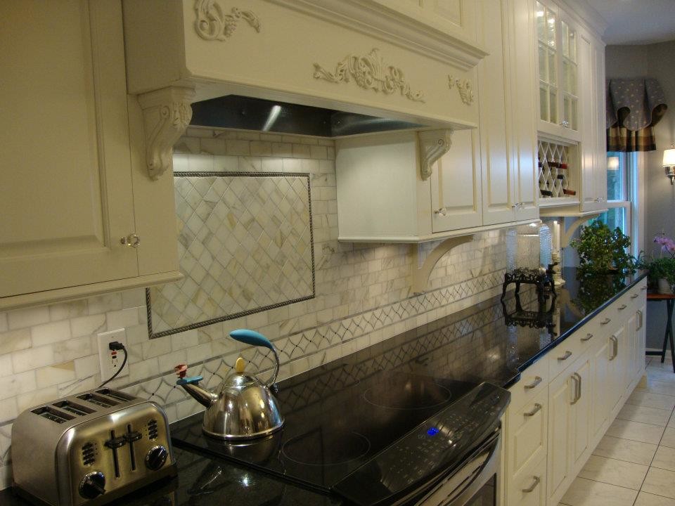 Example of a classic l-shaped eat-in kitchen design in Denver with an undermount sink, raised-panel cabinets, white cabinets, granite countertops, gray backsplash, stone tile backsplash and stainless steel appliances
