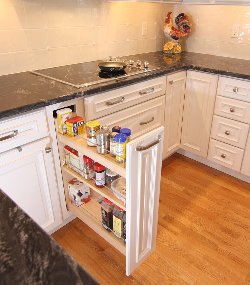 Bild på ett mellanstort vintage kök, med en undermonterad diskho, luckor med upphöjd panel, vita skåp, granitbänkskiva, vitt stänkskydd, stänkskydd i keramik, rostfria vitvaror, ljust trägolv och en halv köksö