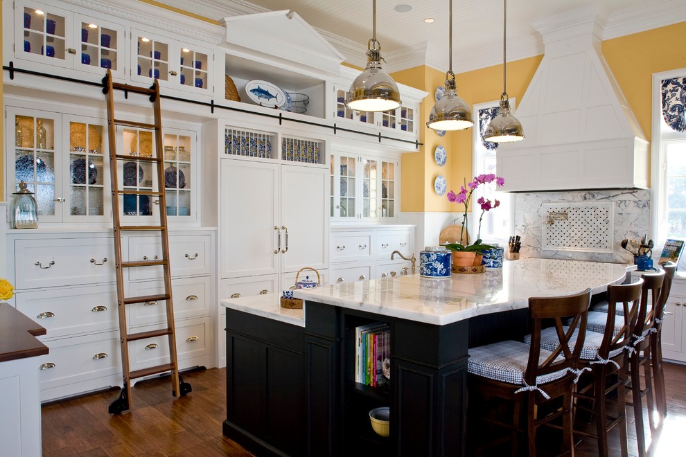 Klassische Küche mit Glasfronten, weißen Schränken, bunter Rückwand, Elektrogeräten mit Frontblende, braunem Holzboden und Kücheninsel in Denver