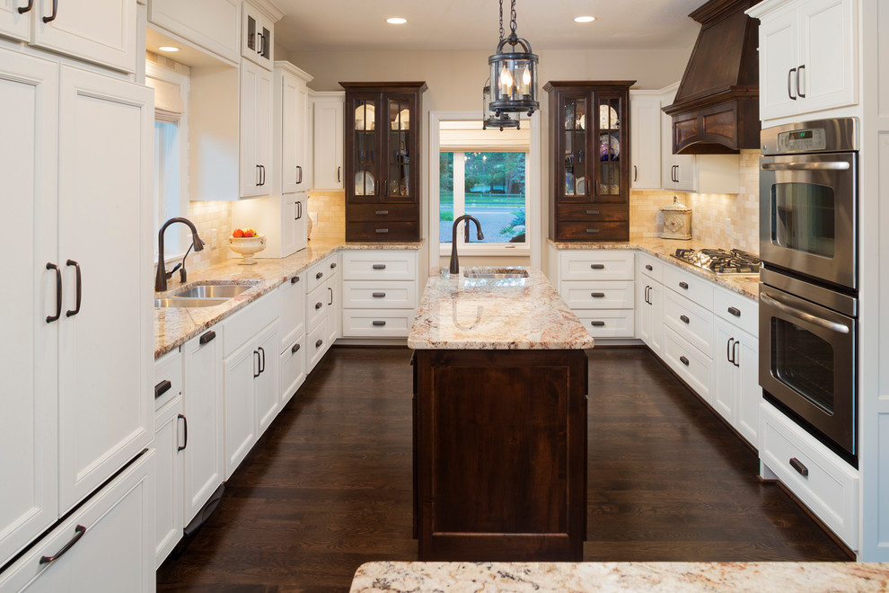 This is an example of a traditional u-shaped kitchen in Minneapolis with a double-bowl sink, recessed-panel cabinets, white cabinets, granite worktops, beige splashback and stainless steel appliances.