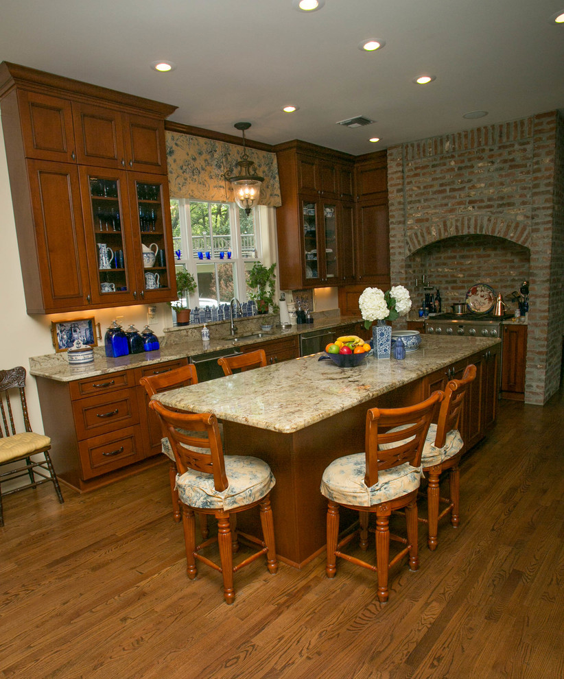 Exempel på ett stort klassiskt u-kök, med en undermonterad diskho, luckor med infälld panel, skåp i mellenmörkt trä, rostfria vitvaror och mellanmörkt trägolv