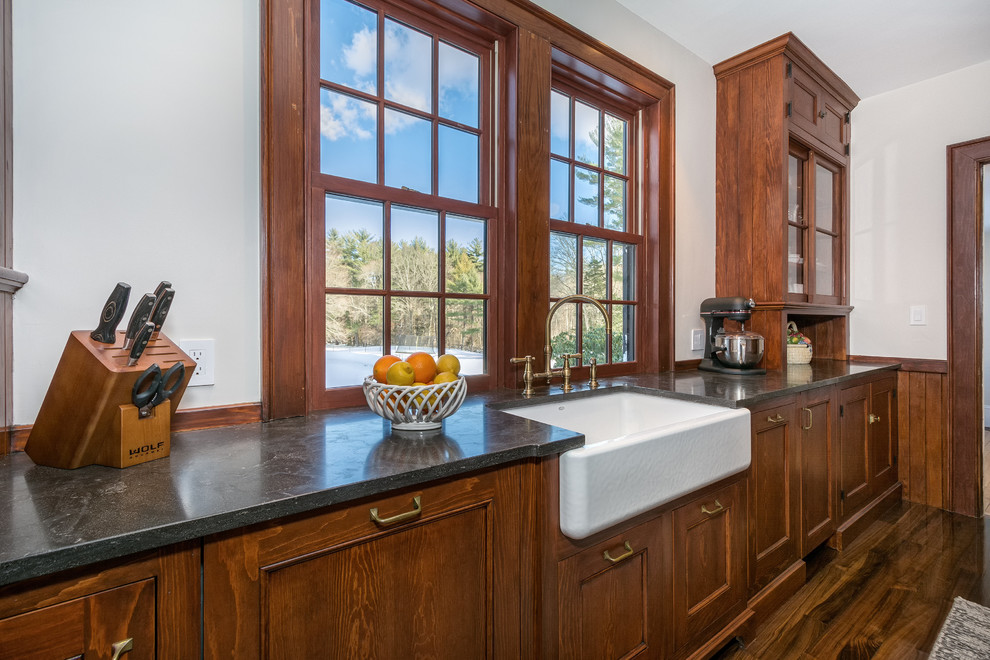 Eat-in kitchen - small traditional galley dark wood floor and brown floor eat-in kitchen idea in Boston with a farmhouse sink, glass-front cabinets, dark wood cabinets, limestone countertops, gray backsplash, mosaic tile backsplash and stainless steel appliances