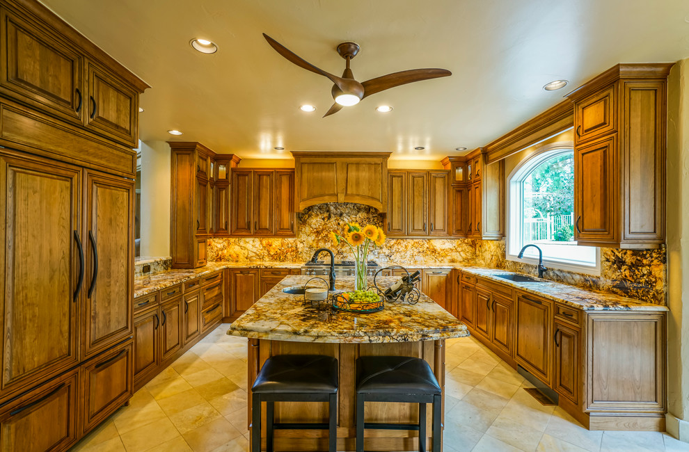 Example of a large mountain style u-shaped travertine floor eat-in kitchen design in Denver with a double-bowl sink, granite countertops, stone slab backsplash, paneled appliances, an island, raised-panel cabinets, dark wood cabinets and multicolored backsplash