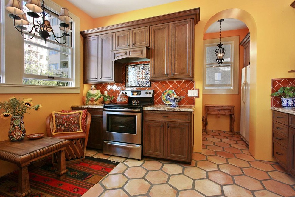 Foto på ett avskilt, mellanstort amerikanskt u-kök, med en undermonterad diskho, luckor med infälld panel, skåp i mellenmörkt trä, granitbänkskiva, orange stänkskydd, stänkskydd i keramik, rostfria vitvaror och klinkergolv i terrakotta
