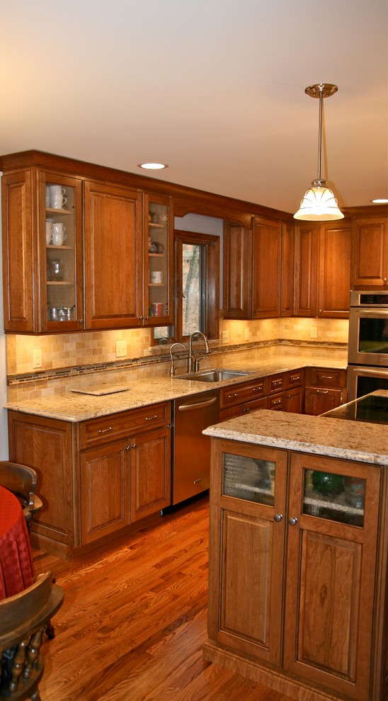 Eat-in kitchen - traditional l-shaped medium tone wood floor eat-in kitchen idea in St Louis with an undermount sink, medium tone wood cabinets, granite countertops, beige backsplash, stainless steel appliances and an island