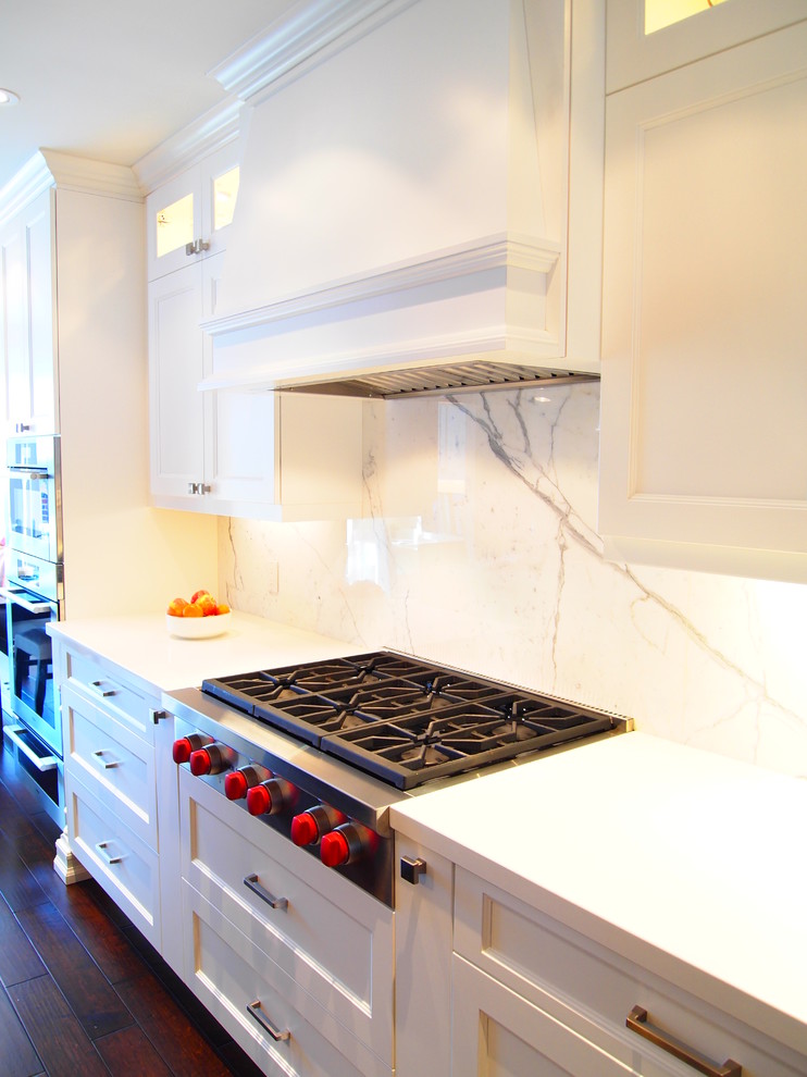 Elegant kitchen photo in Toronto with white cabinets, quartz countertops, white backsplash and stone slab backsplash