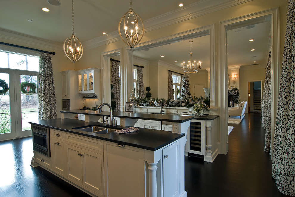Example of a large classic single-wall dark wood floor open concept kitchen design in Charlotte with shaker cabinets, white cabinets, granite countertops, an island, stainless steel appliances and an undermount sink