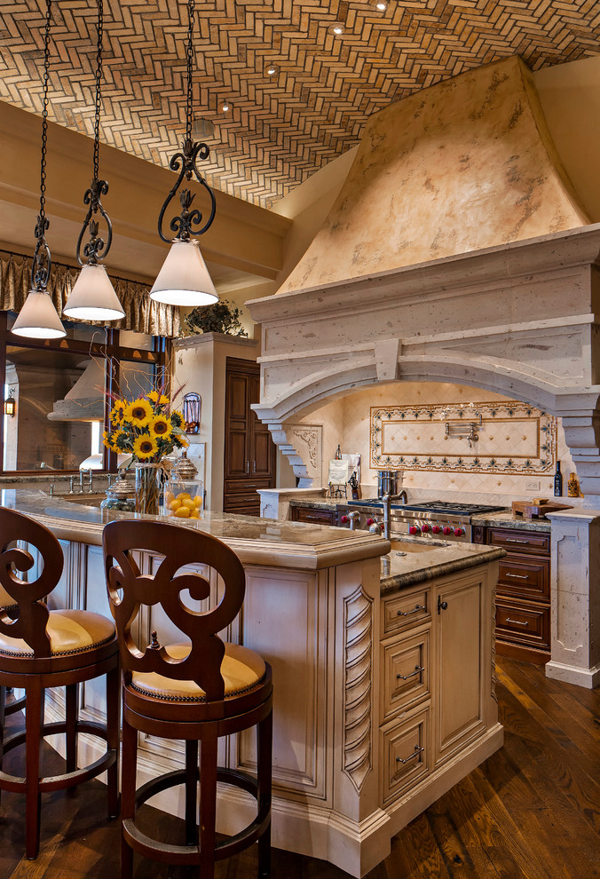 フェニックスにある地中海スタイルのおしゃれなアイランドキッチン (エプロンフロントシンク、レイズドパネル扉のキャビネット、御影石カウンター、パネルと同色の調理設備、無垢フローリング) の写真