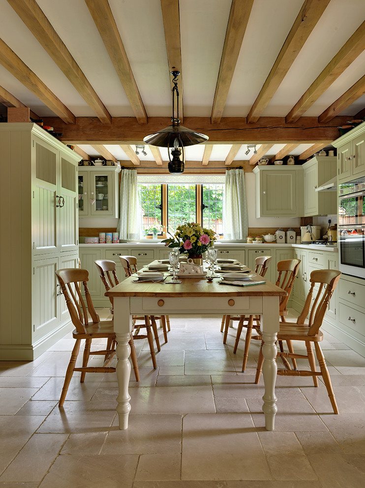 Пример оригинального дизайна: кухня среднего размера в стиле шебби-шик с обеденным столом, фасадами с утопленной филенкой, зелеными фасадами, полом из известняка и бежевым полом без острова