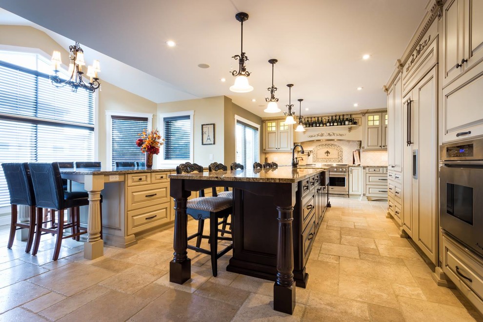 Eat-in kitchen - large traditional u-shaped travertine floor eat-in kitchen idea in Other with a farmhouse sink, raised-panel cabinets, beige cabinets, granite countertops, beige backsplash, stone tile backsplash, paneled appliances and two islands