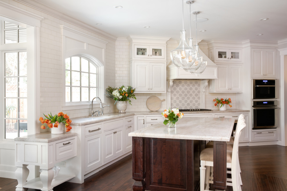 Klassisk inredning av ett grå grått l-kök, med en undermonterad diskho, luckor med upphöjd panel, vita skåp, vitt stänkskydd, stänkskydd i tunnelbanekakel, rostfria vitvaror, korkgolv, en köksö och brunt golv