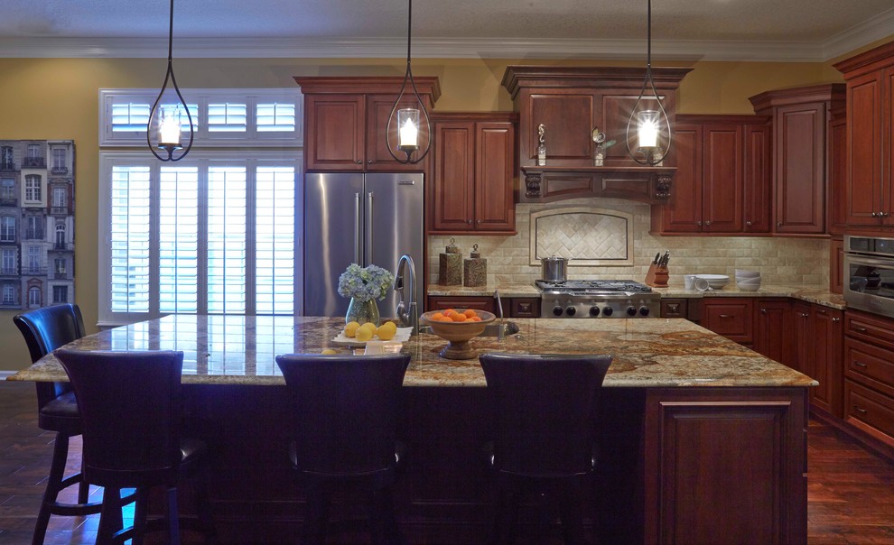 Exempel på ett mellanstort klassiskt kök, med en dubbel diskho, luckor med upphöjd panel, skåp i mörkt trä, granitbänkskiva, beige stänkskydd, stänkskydd i stenkakel, rostfria vitvaror, mellanmörkt trägolv och en köksö
