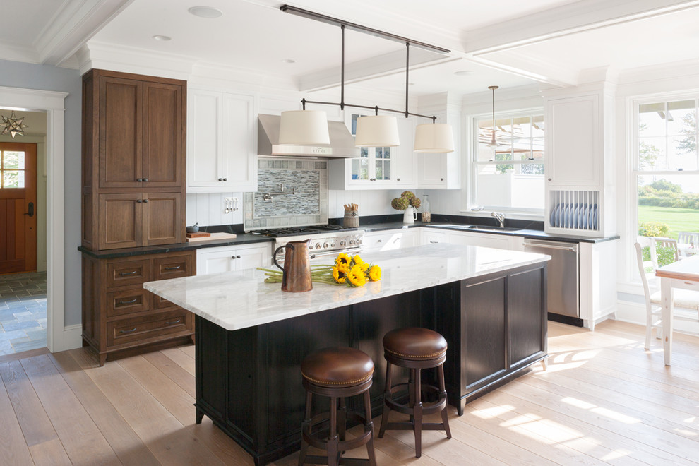 Inspiration for a timeless light wood floor enclosed kitchen remodel in Boston with an undermount sink, beaded inset cabinets, white cabinets, soapstone countertops, stainless steel appliances, an island, black backsplash and stone slab backsplash