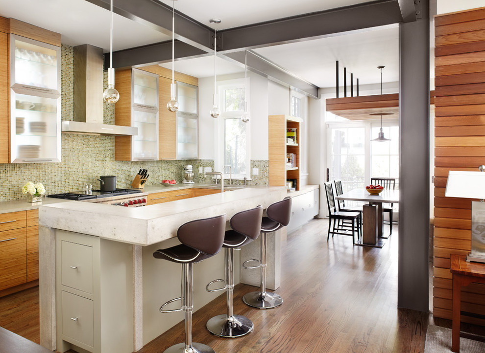 На фото: кухня-гостиная в стиле модернизм с стеклянными фасадами, зеленым фартуком, фартуком из плитки мозаики, техникой из нержавеющей стали и барной стойкой