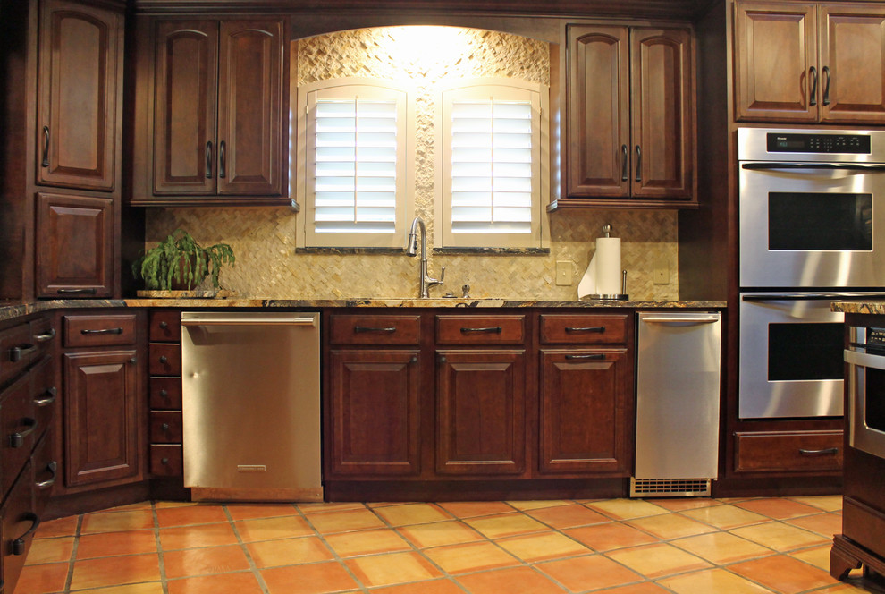 Exempel på ett mellanstort klassiskt kök, med en undermonterad diskho, luckor med upphöjd panel, skåp i mörkt trä, granitbänkskiva, beige stänkskydd, stänkskydd i stenkakel, rostfria vitvaror och klinkergolv i terrakotta