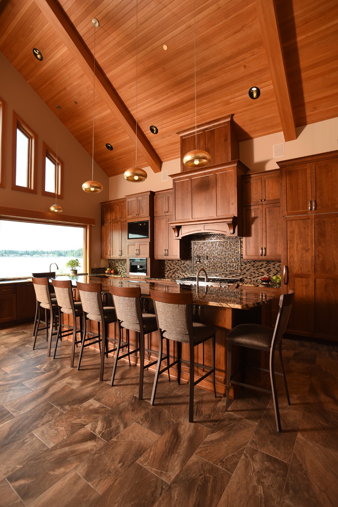Example of a large mountain style l-shaped ceramic tile and multicolored floor open concept kitchen design in Seattle with an undermount sink, shaker cabinets, medium tone wood cabinets, granite countertops, multicolored backsplash, glass tile backsplash, paneled appliances and an island