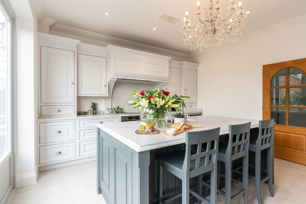 Large traditional l-shaped kitchen in Essex with a submerged sink, raised-panel cabinets, grey cabinets, quartz worktops, white splashback, stainless steel appliances, porcelain flooring, an island, beige floors and white worktops.