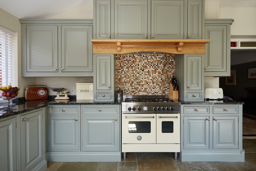На фото: кухня в классическом стиле с врезной мойкой, фасадами с выступающей филенкой, зелеными фасадами, гранитной столешницей и разноцветным полом