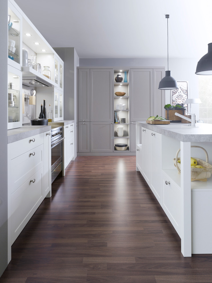 Inspiration for a medium sized traditional l-shaped kitchen/diner in New York with a built-in sink, shaker cabinets, white cabinets, stainless steel appliances, dark hardwood flooring and an island.