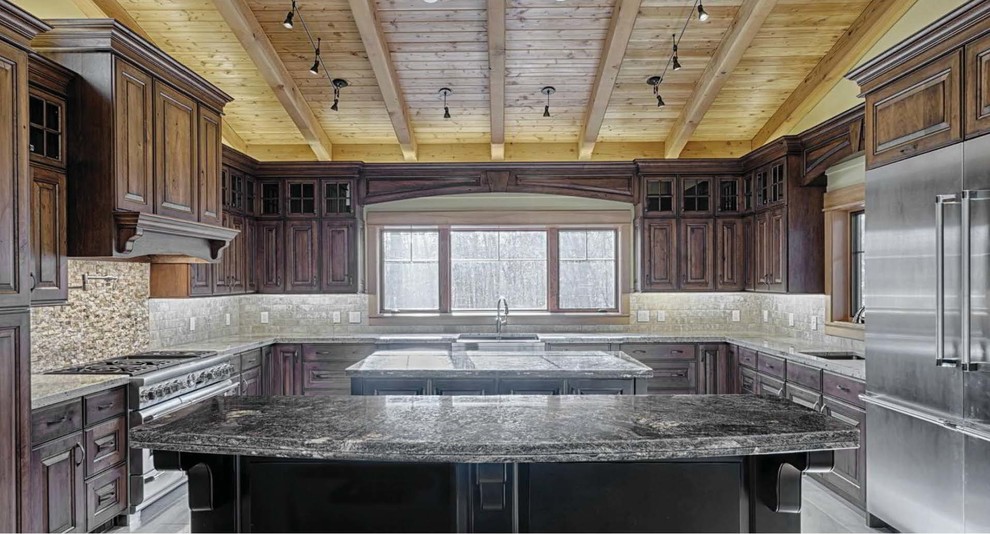 Inredning av ett klassiskt stort u-kök, med luckor med upphöjd panel, skåp i mellenmörkt trä, granitbänkskiva, beige stänkskydd, stänkskydd i keramik, rostfria vitvaror, flera köksöar och en rustik diskho