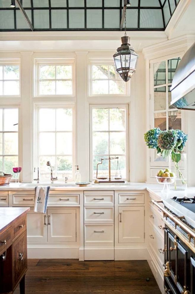 Inspiration för stora klassiska vitt kök, med en rustik diskho, luckor med profilerade fronter, vita skåp, marmorbänkskiva, vitt stänkskydd, stänkskydd i keramik, svarta vitvaror, mörkt trägolv, en köksö och brunt golv
