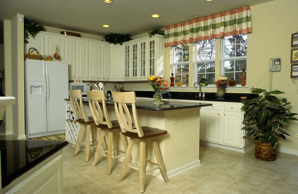Foto di un cucina con isola centrale chic con ante con bugna sagomata, ante bianche, top in granito, paraspruzzi beige e elettrodomestici bianchi