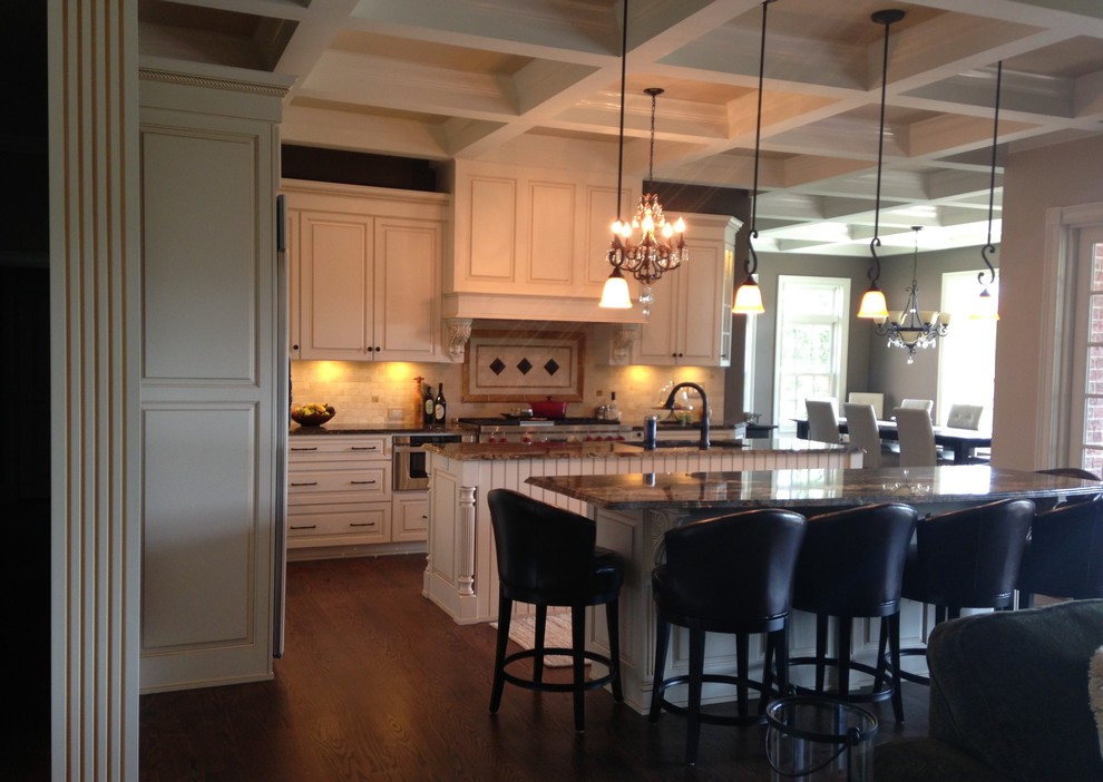 Klassisk inredning av ett kök, med en undermonterad diskho, luckor med upphöjd panel, vita skåp, granitbänkskiva, flerfärgad stänkskydd, stänkskydd i keramik och rostfria vitvaror
