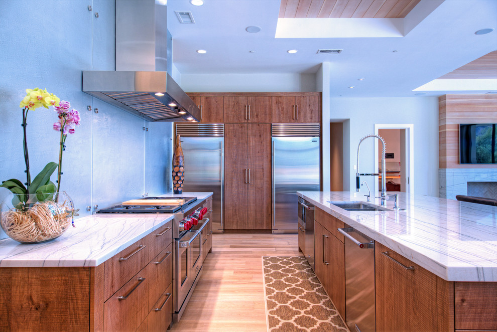 Foto på ett stort funkis kök, med en undermonterad diskho, släta luckor, skåp i mellenmörkt trä, granitbänkskiva, rostfria vitvaror, ljust trägolv och en köksö
