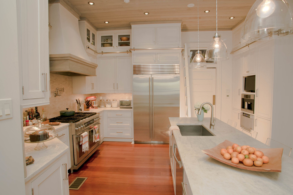 Inspiration for a medium sized classic u-shaped enclosed kitchen in New Orleans with a single-bowl sink, recessed-panel cabinets, white cabinets, marble worktops, mosaic tiled splashback, stainless steel appliances, medium hardwood flooring and an island.
