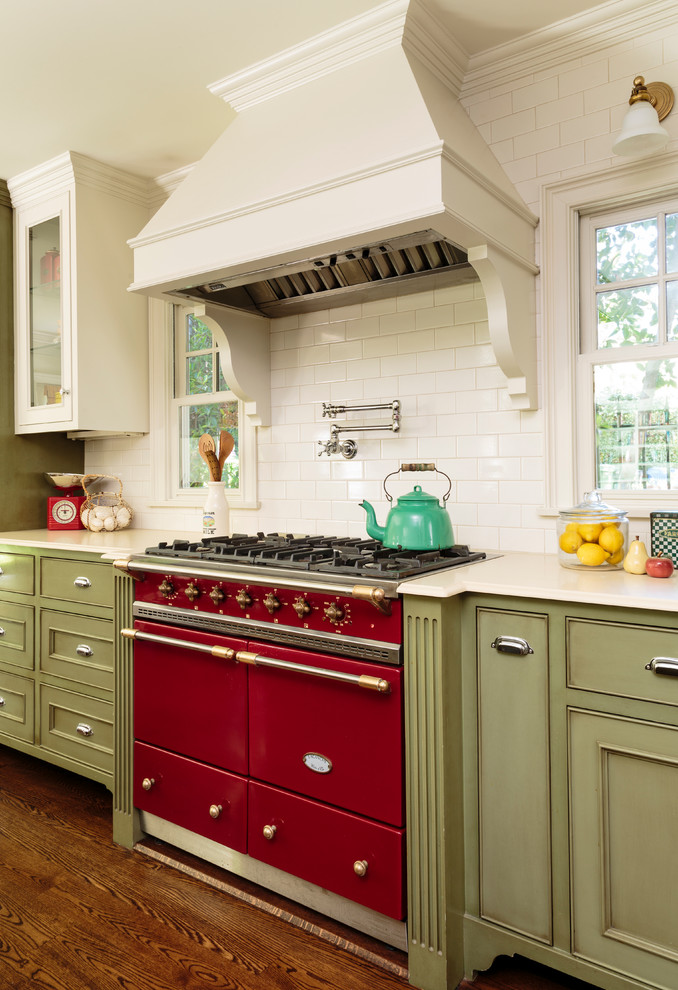 Bild på ett stort vintage kök, med luckor med infälld panel, gröna skåp, bänkskiva i kvarts, vitt stänkskydd, stänkskydd i keramik, rostfria vitvaror och mörkt trägolv