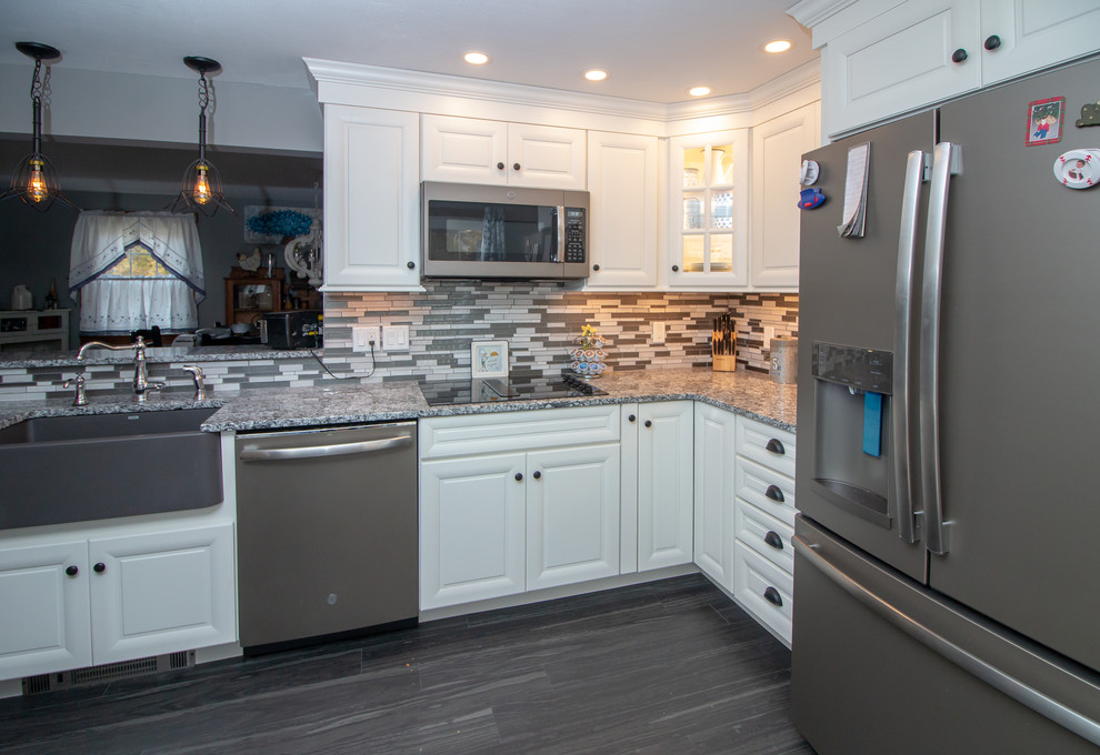 Mid-sized elegant galley vinyl floor and gray floor eat-in kitchen photo in Manchester with a farmhouse sink, flat-panel cabinets, white cabinets, granite countertops, gray backsplash, glass sheet backsplash, stainless steel appliances, no island and multicolored countertops