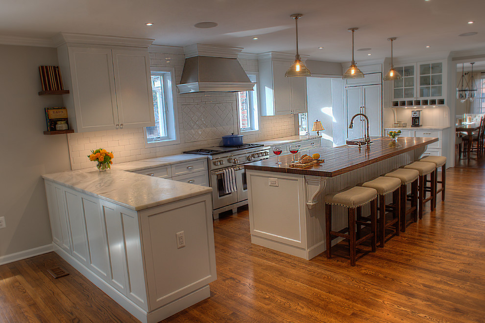 ワシントンD.C.にある広いトラディショナルスタイルのおしゃれなキッチン (エプロンフロントシンク、落し込みパネル扉のキャビネット、白いキャビネット、白いキッチンパネル、サブウェイタイルのキッチンパネル、パネルと同色の調理設備、濃色無垢フローリング) の写真