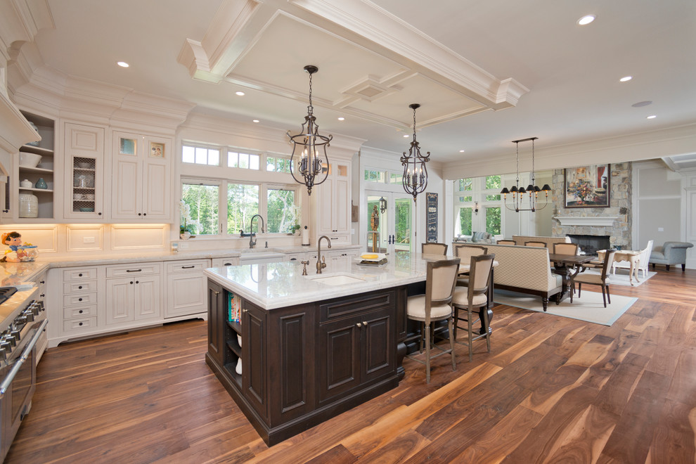 Inspiration for a timeless l-shaped medium tone wood floor open concept kitchen remodel in New York with a single-bowl sink, raised-panel cabinets, white cabinets, window backsplash, stainless steel appliances and an island