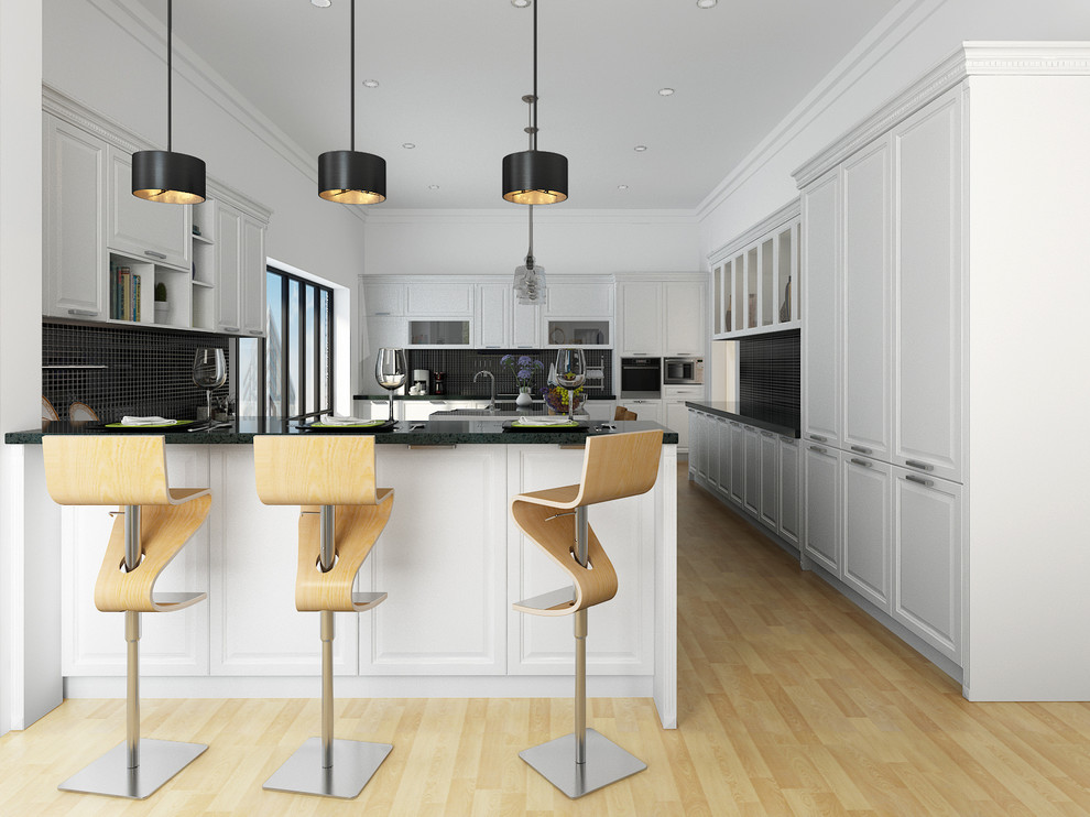 高級な広いトランジショナルスタイルのおしゃれなアイランドキッチン (白いキャビネット、黒いキッチンパネル、シルバーの調理設備、淡色無垢フローリング、ベージュの床、レイズドパネル扉のキャビネット) の写真