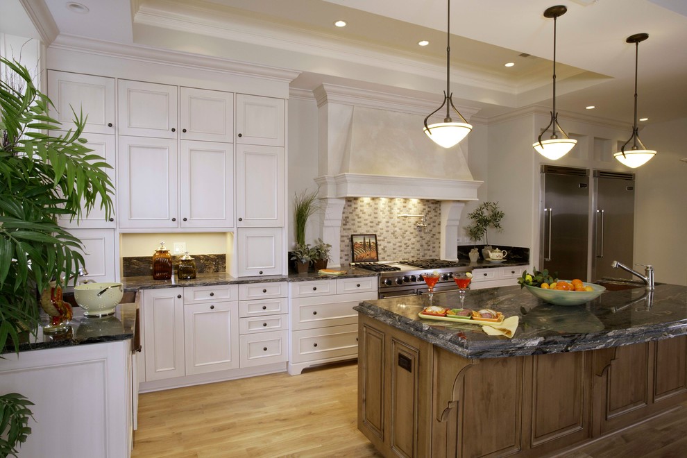 Example of a large classic l-shaped light wood floor open concept kitchen design in Chicago with an undermount sink, recessed-panel cabinets, white cabinets, granite countertops, beige backsplash, stone tile backsplash, stainless steel appliances and an island