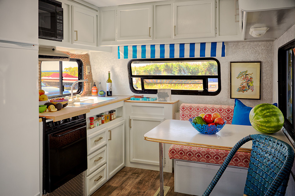 Inspiration for a small eclectic l-shaped medium tone wood floor eat-in kitchen remodel in Philadelphia with a drop-in sink, recessed-panel cabinets, white cabinets, wood countertops, black appliances and no island