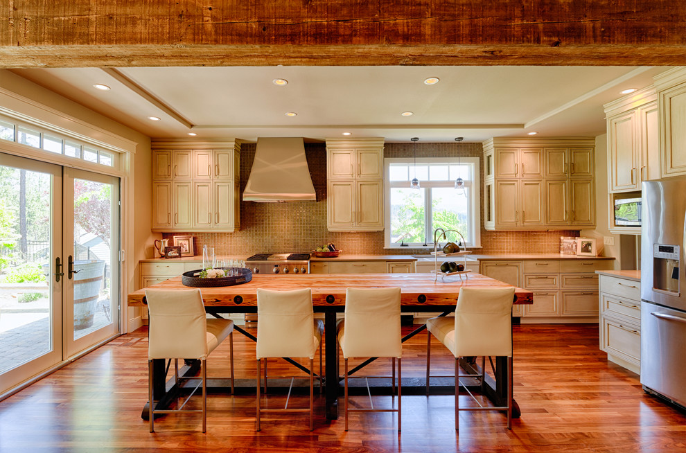 Example of a large transitional l-shaped dark wood floor open concept kitchen design in Seattle with a farmhouse sink, recessed-panel cabinets, distressed cabinets, quartz countertops, gray backsplash, glass tile backsplash, stainless steel appliances and an island
