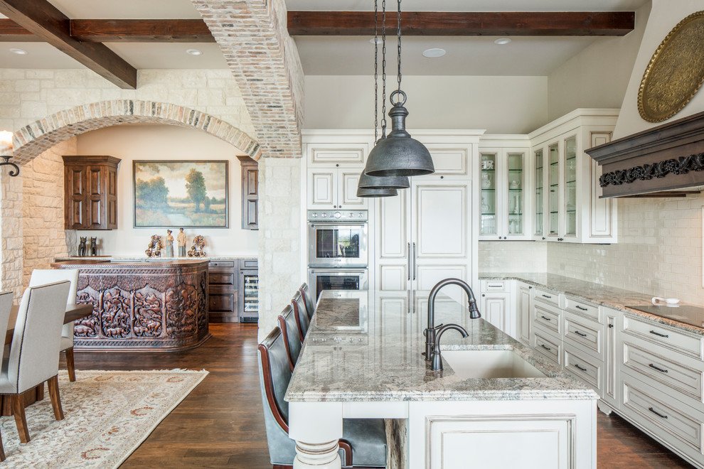 Inspiration for a mediterranean l-shaped kitchen in Austin with a submerged sink, beige cabinets, beige splashback, integrated appliances, an island and medium hardwood flooring.