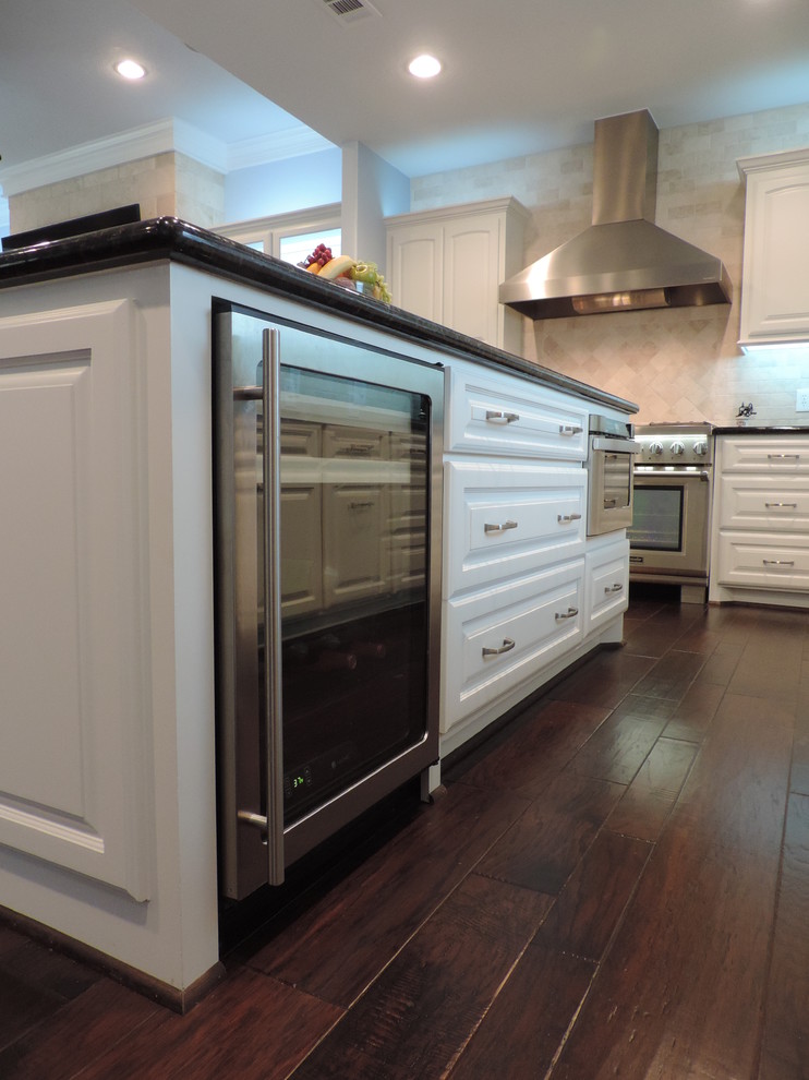 Exempel på ett mellanstort klassiskt kök, med luckor med upphöjd panel, vita skåp, granitbänkskiva, beige stänkskydd, stänkskydd i stenkakel, rostfria vitvaror, mörkt trägolv och en köksö