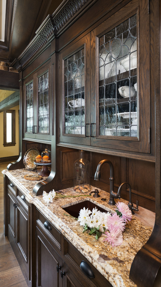 Traditional kitchen/diner in Minneapolis with a submerged sink, recessed-panel cabinets, dark wood cabinets, brown splashback, stainless steel appliances, light hardwood flooring and an island.