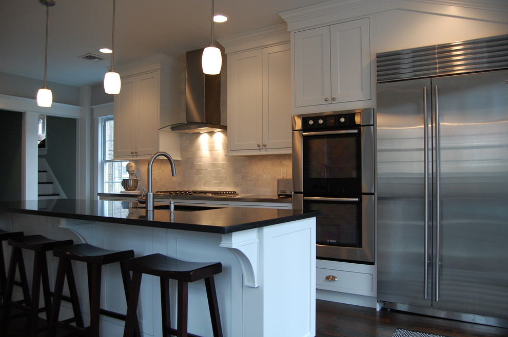 Example of a mid-sized transitional dark wood floor eat-in kitchen design in New York with white cabinets, stainless steel appliances, an island, an undermount sink, shaker cabinets, stainless steel countertops, white backsplash and subway tile backsplash