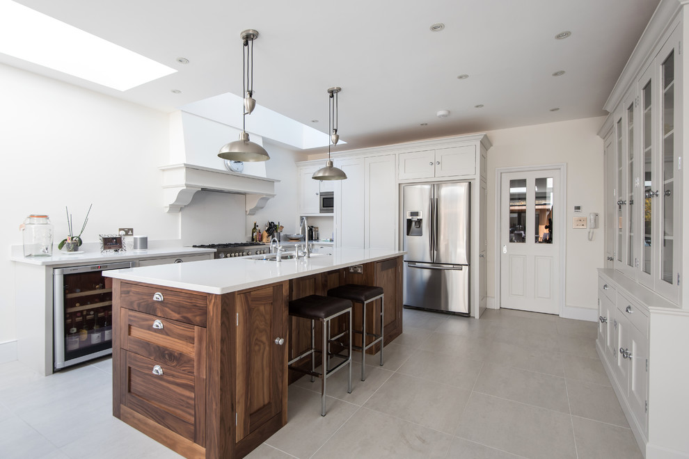 Inspiration for a traditional kitchen in London with a double-bowl sink, shaker cabinets, white cabinets, stainless steel appliances and an island.