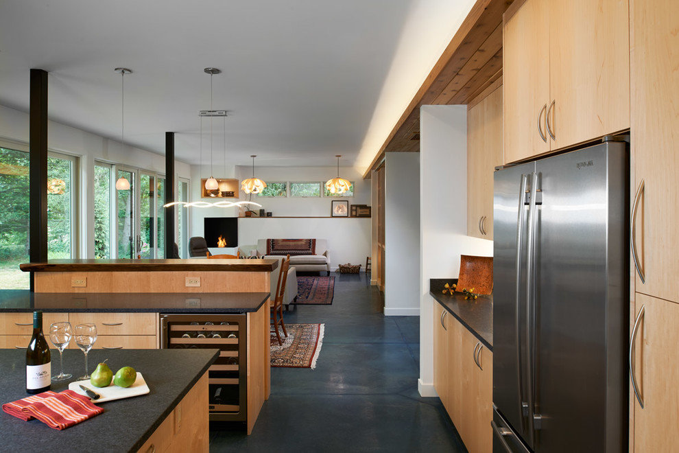 Idee per una cucina minimal di medie dimensioni con ante lisce, ante in legno chiaro, top in granito, elettrodomestici in acciaio inossidabile, pavimento in cemento, lavello sottopiano, pavimento blu e top nero