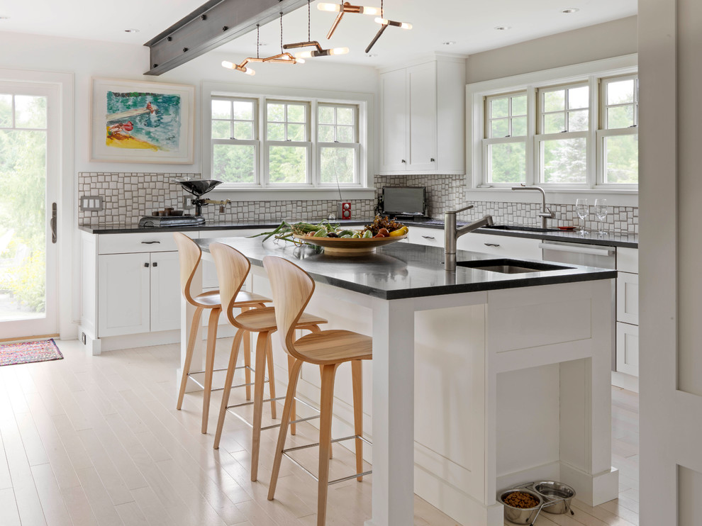 Idéer för ett modernt l-kök, med en undermonterad diskho, skåp i shakerstil, vita skåp, vitt stänkskydd, stänkskydd i mosaik, rostfria vitvaror, ljust trägolv, en köksö och beiget golv