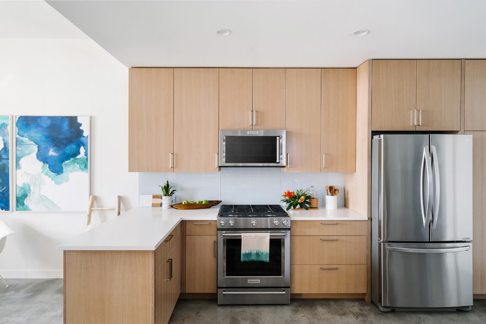 Bild på ett mellanstort funkis kök, med släta luckor, skåp i ljust trä, bänkskiva i kvartsit, vitt stänkskydd, rostfria vitvaror, betonggolv, en köksö, grått golv, en undermonterad diskho och glaspanel som stänkskydd