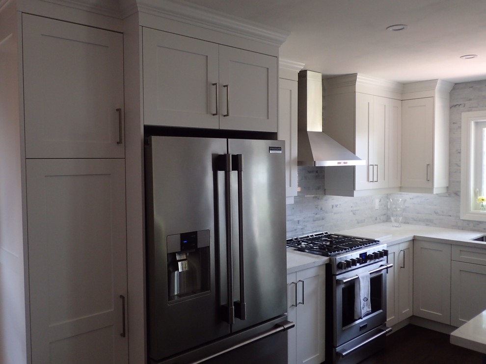Imagen de cocinas en L clásica renovada grande con armarios estilo shaker, puertas de armario blancas, electrodomésticos de acero inoxidable y una isla