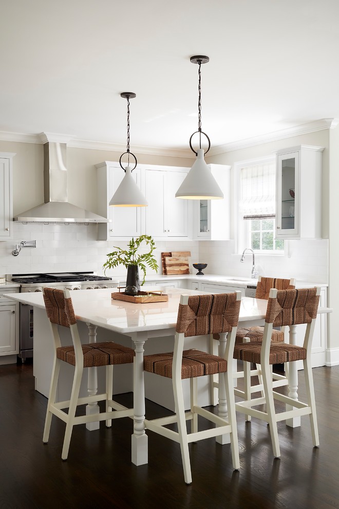 This is an example of a traditional l-shaped kitchen in Philadelphia with a submerged sink, shaker cabinets, white cabinets, white splashback, stainless steel appliances, dark hardwood flooring, an island, brown floors and white worktops.