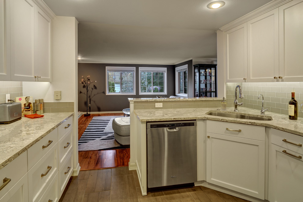 This is an example of a small traditional u-shaped open plan kitchen in Seattle with a submerged sink, beaded cabinets, white cabinets, engineered stone countertops, grey splashback, glass tiled splashback, stainless steel appliances, porcelain flooring and a breakfast bar.