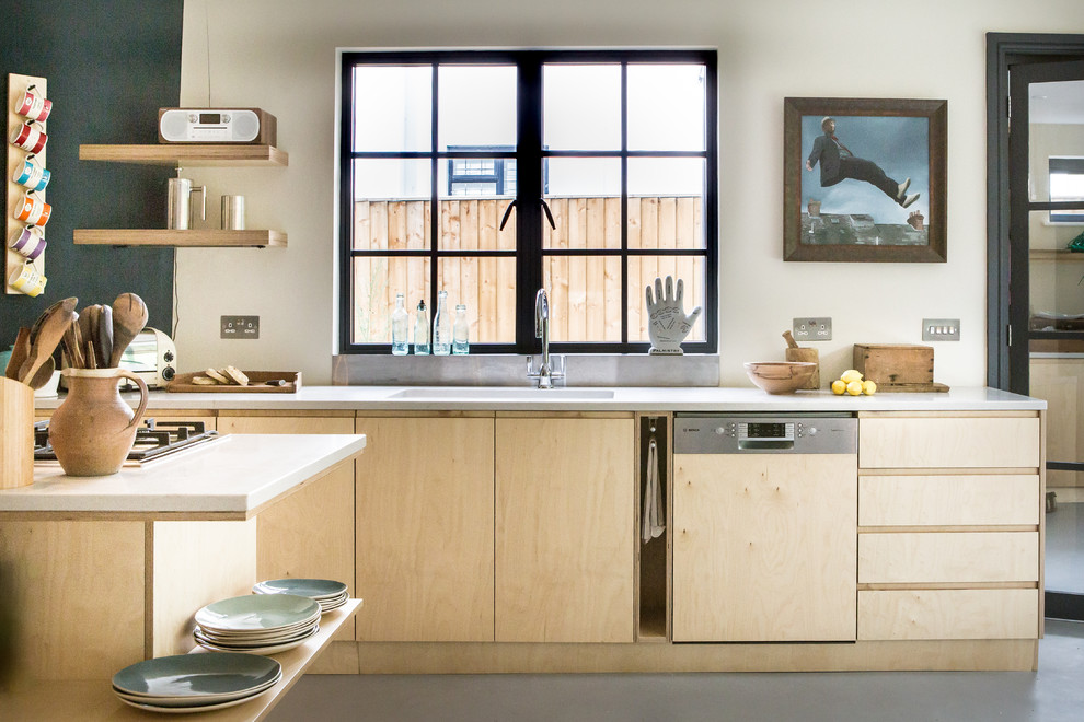 Photo of a scandinavian kitchen in Oxfordshire with a single-bowl sink, flat-panel cabinets, light wood cabinets, window splashback, integrated appliances, an island, grey floors and white worktops.